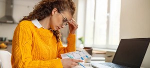mulher preocupada lendo contas na frente do computador