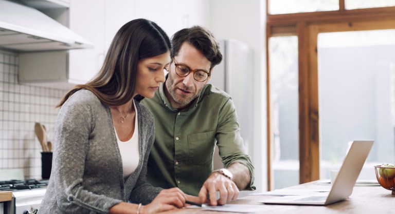 casal fazendo anotações para representar "controle financeiro"