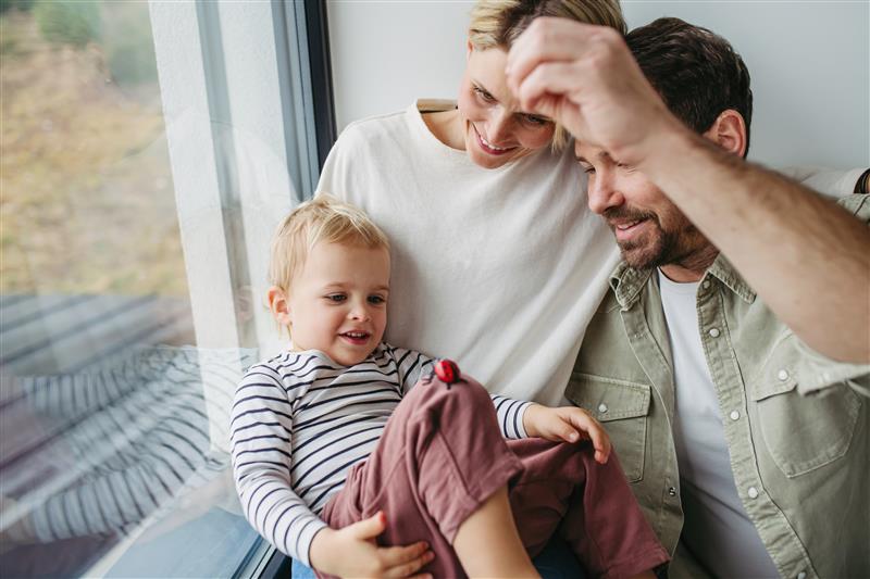 Família feliz compartilhando momentos de alegria e amor em casa, com uma criança sorridente sorrindo e uma mulher com um homem, celebrando a felicidade familiar.