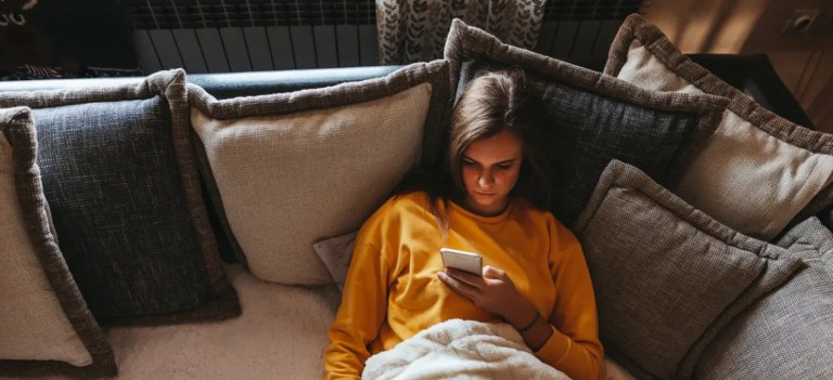 mulher deitada no sofá mexendo no celular