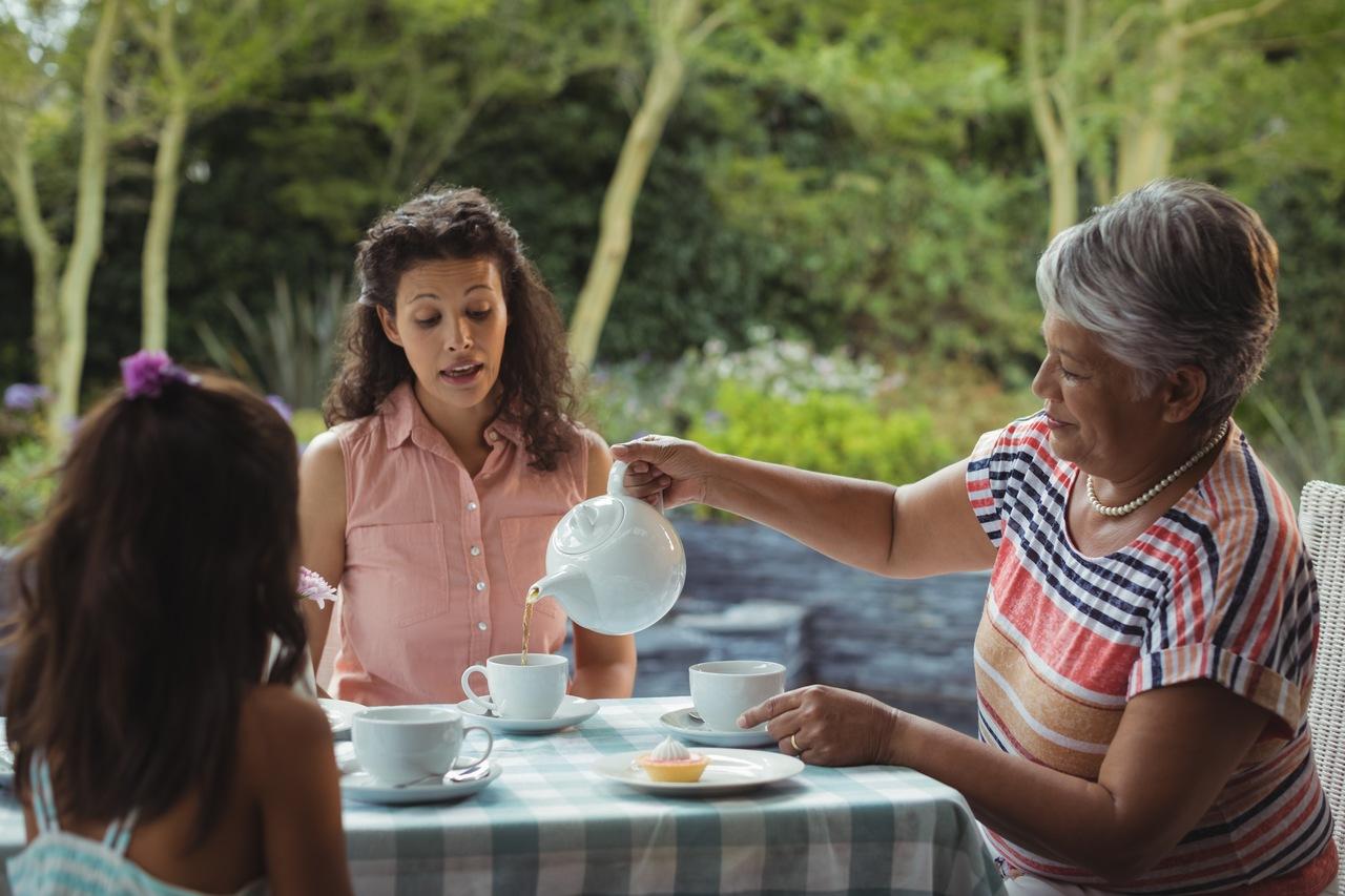 Família reunida em uma mesa no quintal, comendo durante a tarde.