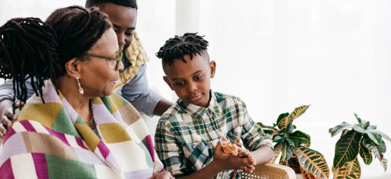 Família feliz desfrutando de um momento de convivência em casa, com o idoso sorrindo e a criança brincando.