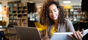 mulher no computador lendo um caderno