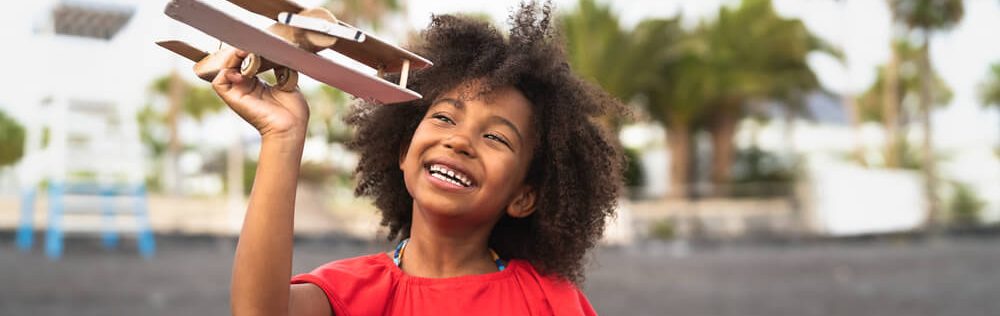 criança feliz segurando um avião de brinquedo em um parque