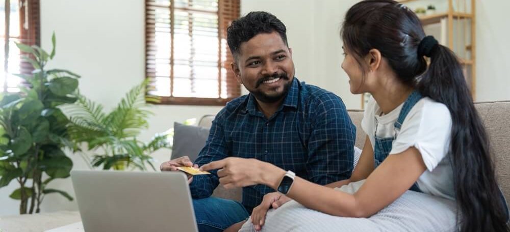Casal usando o notebook sentados no sofá