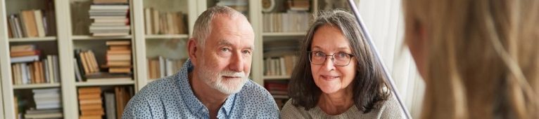 Casal de idosos atentos conversando com uma mulher