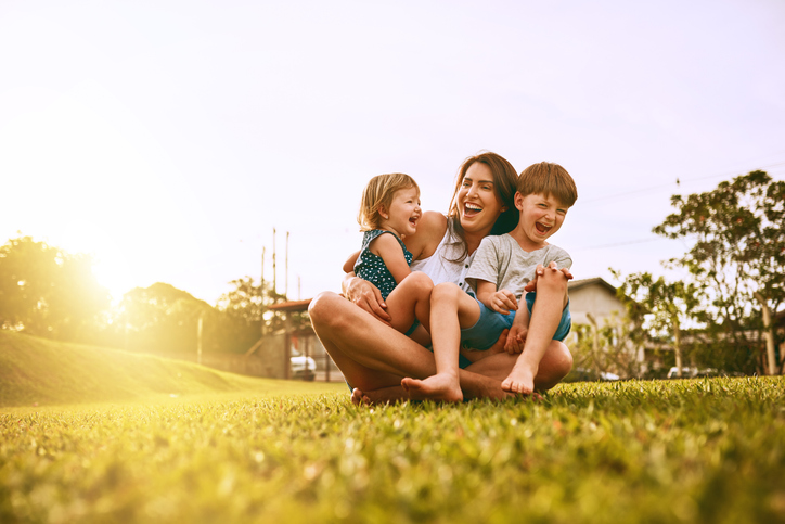 mãe sentada no gramado com os filhos