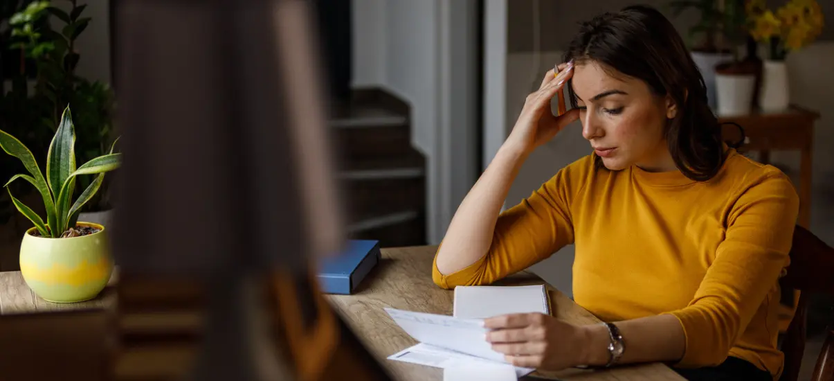 mulher preocupada usando o computador e lendo documentos