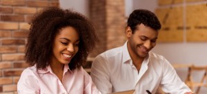 Homem e mulher sorrindo enquanto trabalham juntos em um ambiente de escritório.
