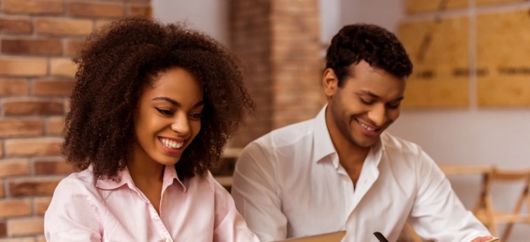 Homem e mulher sorrindo enquanto trabalham juntos em um ambiente de escritório.