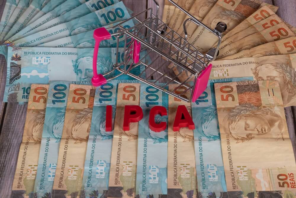 cédulas de dinheiro ilustradas com um mini carrinho de compras caído sob a palavra IPCA em vermelho