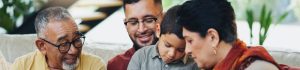 Família reunida em um momento de interação, onde avós, pais e um filho estudam juntos em um tablet.