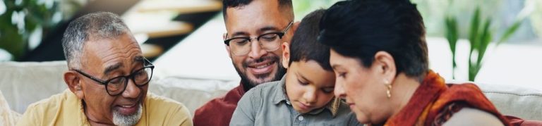 Família reunida em um momento de interação, onde avós, pais e um filho estudam juntos em um tablet.