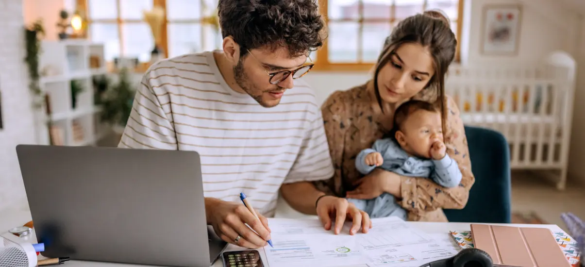 imagem de pais com um bebe no colo fazendo contas
