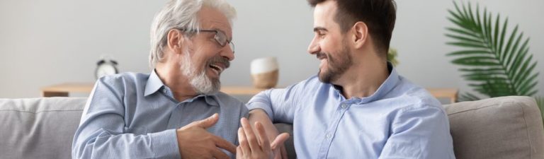 Imagem de um avô e seu neto sorrindo e conversando em um sofá, transmitindo alegria e conexão familiar. Ideal para ilustrar momentos especiais entre gerações.