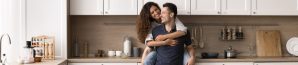 Casal feliz em cozinha moderna, demonstrando amor e cumplicidade enquanto desfrutam de momentos a dois.