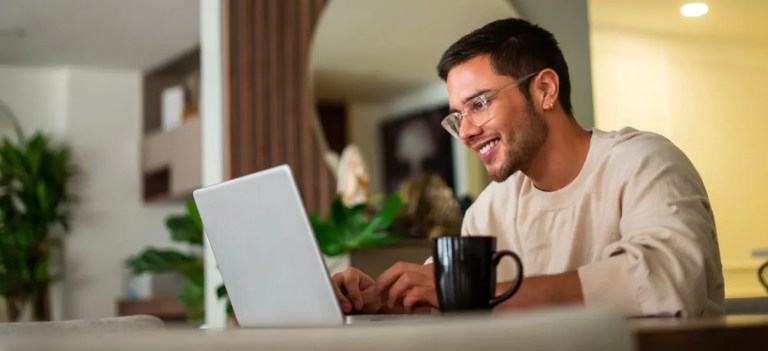 homem procurando no computador sentado na mesa