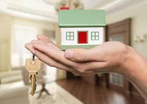 miniatura de casa na mão de uma pessoa com chave da casa nova de aluguel