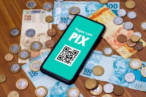 Cédulas e moedas sobre uma mensa, juntamente com um celular.