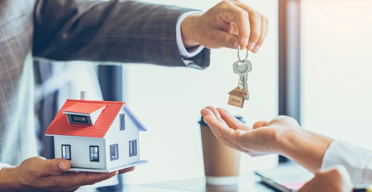 Homem entregando uma chave de casa após fechar o contrato de aluguel.