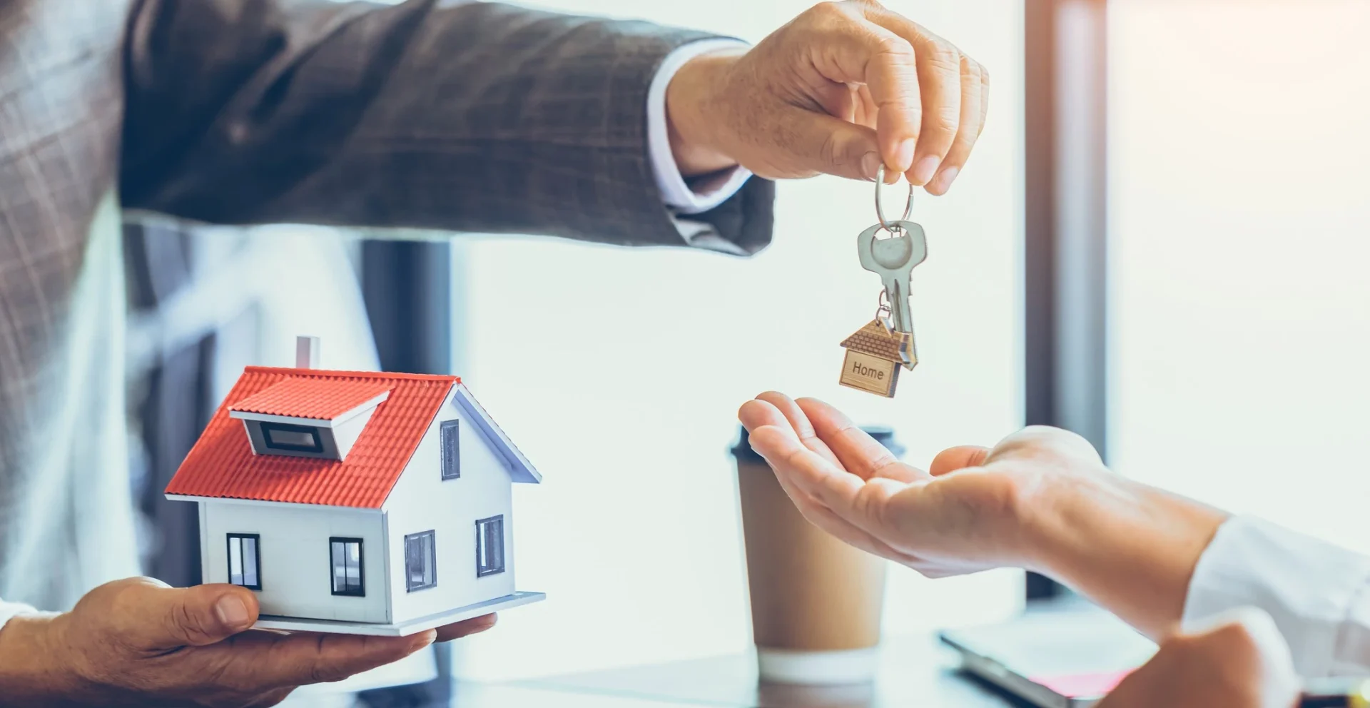 Homem entregando uma chave de casa após fechar o contrato de aluguel.