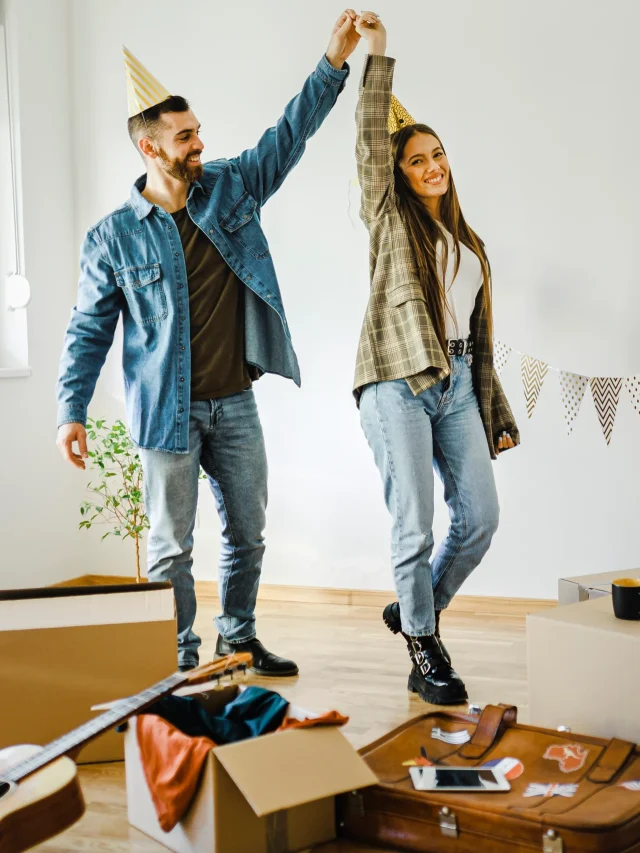 Casal dançando em pé com chapeu de aniversário.
