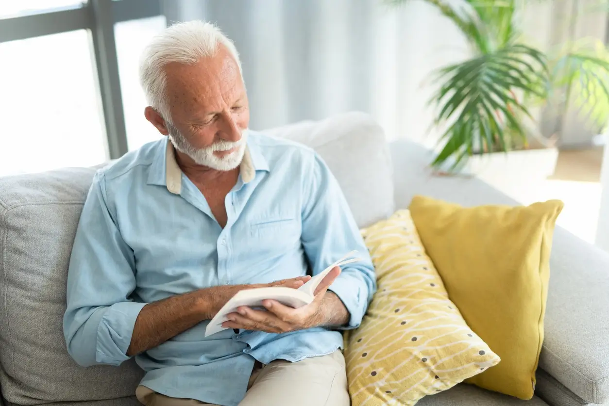 homem idoso lendo sentado no sofá