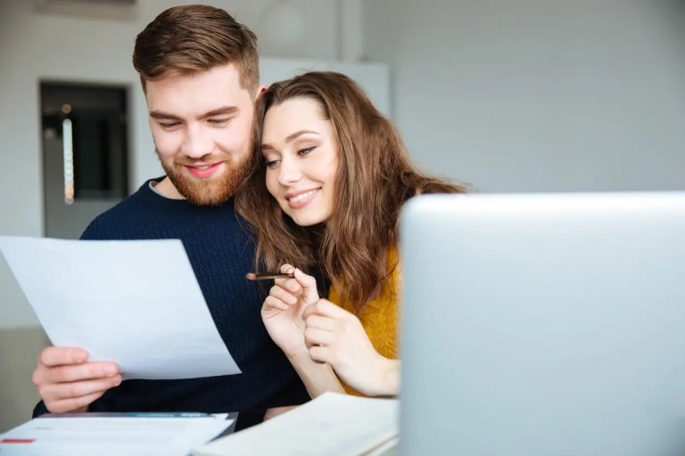 Casal feliz lendo papel à sua frente