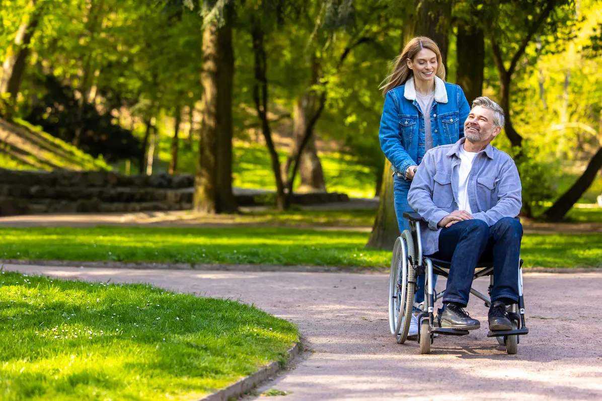 mulher andando com o homem na cadeira de rodas em um parque