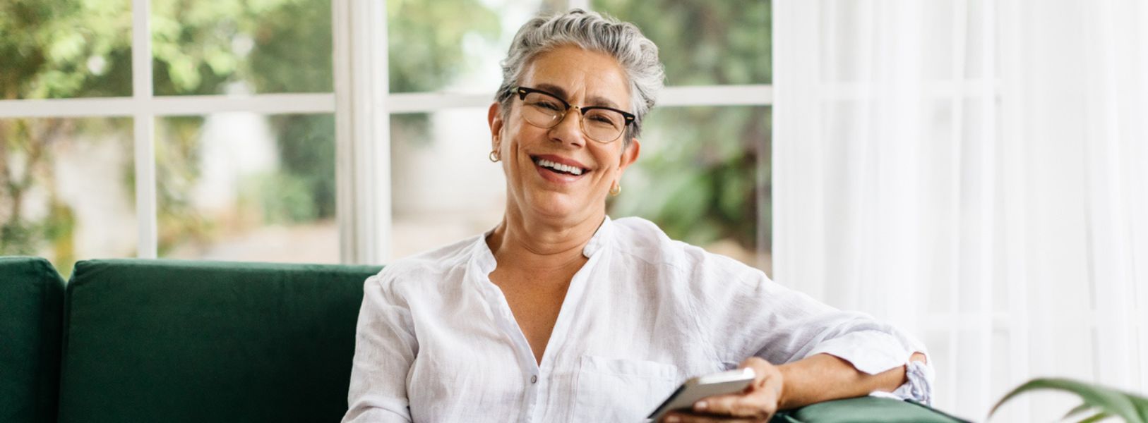 mulher mais velha sentada num sofá sorrindo
