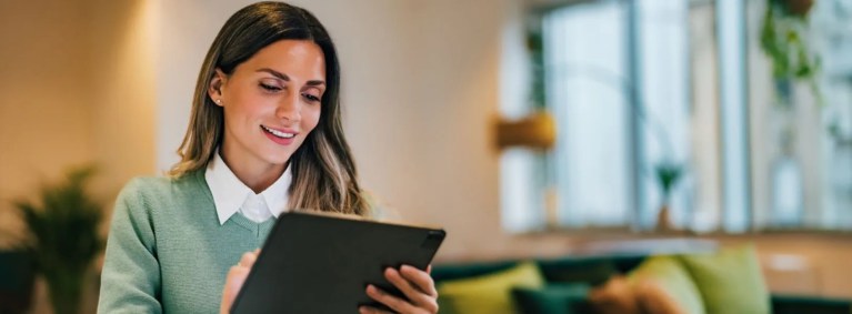 mulher sentada ao lado de uma mesa, segurando um tablet