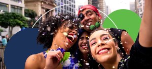 Grupo de amigos se divertindo em uma festa de carnaval, sorrindo e jogando confete, em um ambiente urbano vibrante.