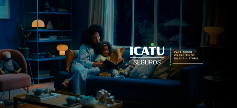 Imagem retratando mãe e filha sentadas confortavelmente no sofá, lendo juntas. A cena transmite uma sensação de acolhimento e segurança, destacando a mensagem da ICATU Seguros.