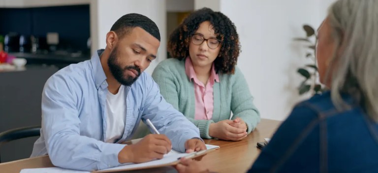 imagem de um casal assinando documentos em uma mesa