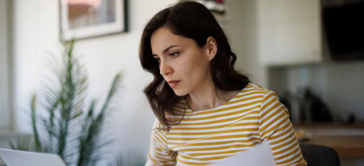 imagem de uma mulher sentada na sala olhando para documentos