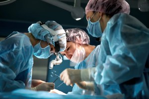 Equipe de cirurgiões realizando uma cirurgia com precisão e foco, usando equipamentos médicos especializados em um ambiente hospitalar.
