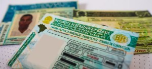 Documentos e carteiras de motorista do Brasil, focados em habilitação e registro de veículos, sobre uma mesa com fundo branco. Itens usados para documentos oficiais.