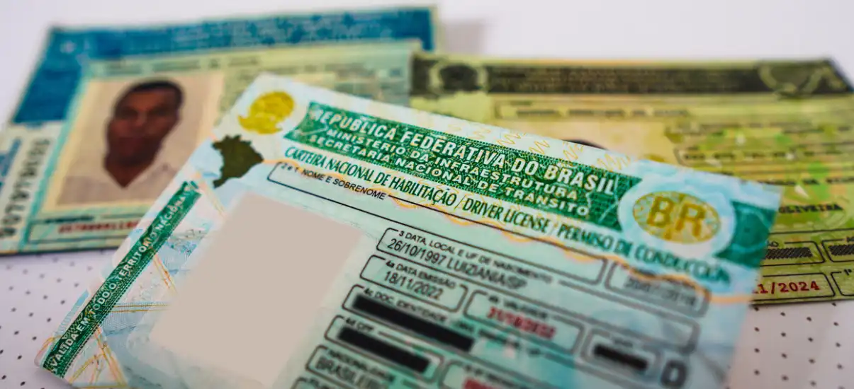 Documentos e carteiras de motorista do Brasil, focados em habilitação e registro de veículos, sobre uma mesa com fundo branco. Itens usados para documentos oficiais.