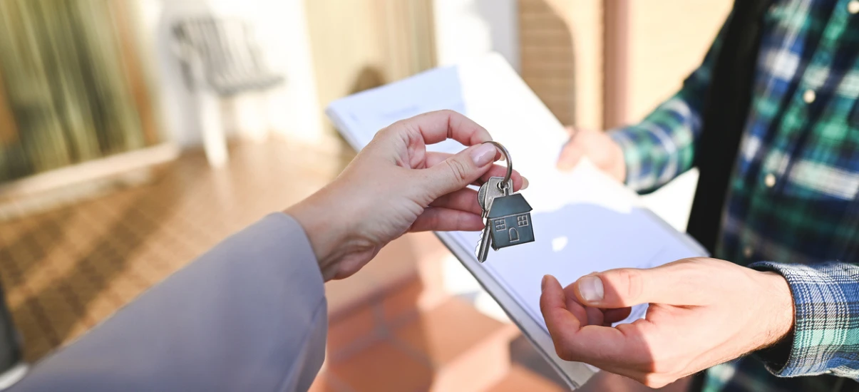Pessoa entregando chave de imóvel em uma negociação imobiliária, representando venda ou aluguel de imóveis, com foco em transações imobiliárias.