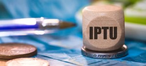 Tela de votação de IPTU com foco no imposto brasileiro, mostrando uma urna de coleta com moedas ao lado, simbolizando arrecadação de impostos no Brasil.